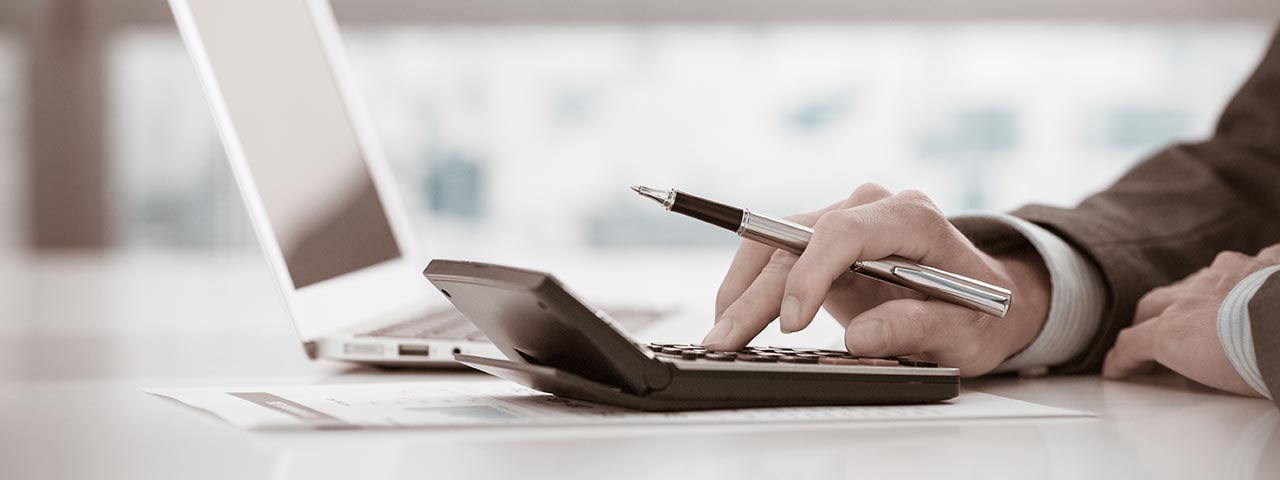 Man using a calculator at his desk Cost Accounting